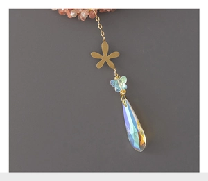 Detail of gold flower charm with blue butterfly bead and AB crystal teardrop pendant