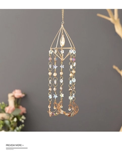 Macro detail of golden suncatcher with pyramid frame, crystal drop and moon stone charms