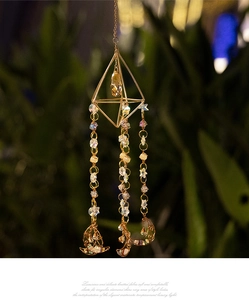 Detail of golden geometric sun catcher with champagne crystal and celestial charms