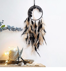 Detail of Tree of Life dream catcher with black stones and natural feathers on white wall