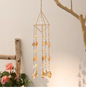 Detail of citrine suncatcher featuring geometric gold frame and amber crystal drops