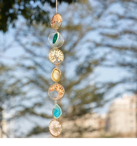 Close-up of handmade tree of life pendants and colorful agate slices hanging on a chain