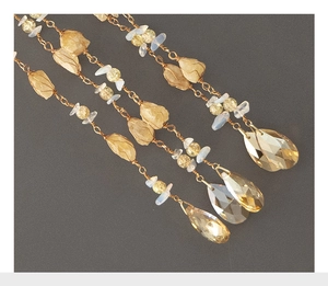 Detail of handmade suncatcher with citrine crystals and golden metal chains on dark base