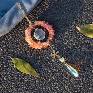 Watermelon crystal suncatcher with faceted glass ball and teardrop pendant in golden light
