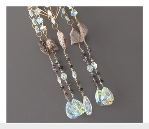 Close-up of amethyst stones and iridescent teardrop crystal pendant on gold wire