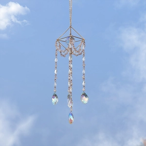 Garden sun catcher with gold geometric frame and iridescent crystal prisms against sky