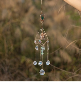 Macro detail of geometric metal suncatcher with green raw stone and crystal spheres