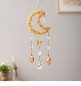 Detail of moon-shaped suncatcher with yellow citrine stones and gold butterfly pendant
