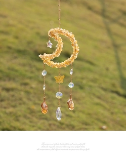 Detail of bohemian moon suncatcher with citrine stones and butterfly charms in sunlight