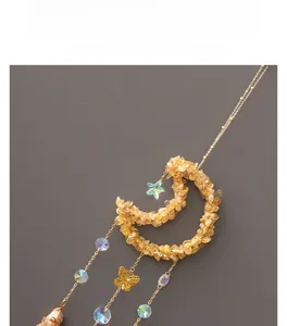 Detail of crescent moon suncatcher with yellow citrine crystals and golden butterfly pendant
