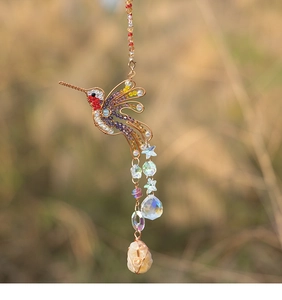 Detail of wire-wrapped hummingbird suncatcher with colorful crystals and natural gemstone