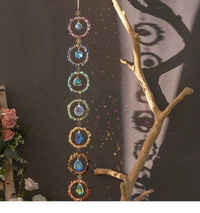 Macro detail of 7 chakra natural stone suncatcher casting rainbow light on gray wall