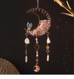 Detail of moon-shaped crystal suncatcher with pink raw stones and white crystal pendants