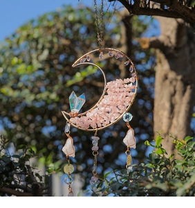 Detail of moon-shaped suncatcher with pink crystals and iridescent beads hanging outdoors