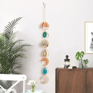 Vertical seven-chakra tree of life wall hanging with natural crystals on a white wall