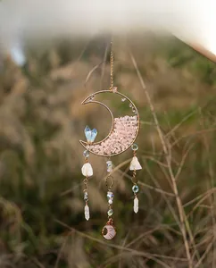Detail of pink crystal moon suncatcher with white hanging stones in hand