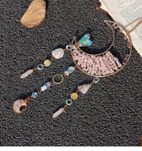 Detail of moon-shaped suncatcher with pink crystals and metallic wire on vintage background