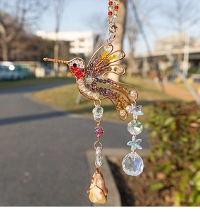 Detail of hummingbird crystal suncatcher with natural stones and metal wire wrap design