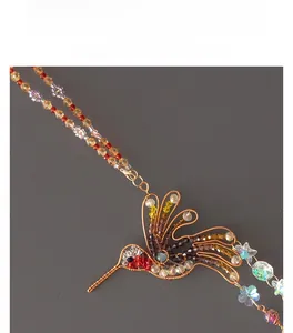 Detailed macro shot of a handmade wire-wrapped hummingbird with colorful crystal stones