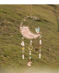 Close-up of pink crystal stones and moon-shaped wire wrap suncatcher on grass background