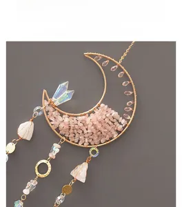 Detail of moon-shaped suncatcher with pink natural crystals and golden wire wrap