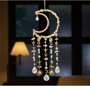 Detail of moon-shaped dreamcatcher with yellow crystals and golden celestial pendants
