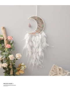 Detail of moon-shaped dream catcher with tree of life crystal stones and white feathers