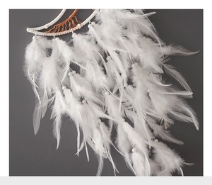 Close-up of white feathers and beaded accents on a handmade crescent moon dreamcatcher
