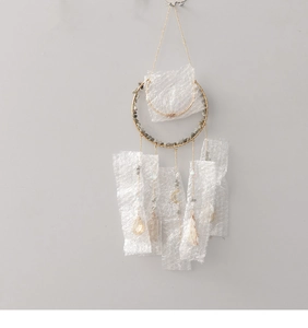 Detail of tree of life suncatcher with grey stones and gold metal ring hanging on wall