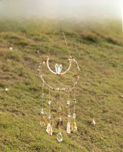 Detail of moon-shaped suncatcher with natural stones and crystals in golden frames