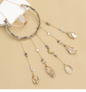 Detail of moon-shaped suncatcher with natural raw stones and crystal prisms hanging