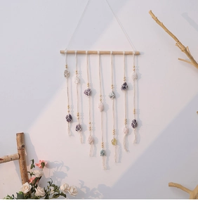 Close-up of bohemian wall hanging featuring natural gemstones and cotton tassels