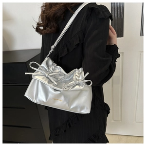 Detailaufnahme der silbernen gerafften Schultertasche mit Doppelschleifen und Metallic-Effekt