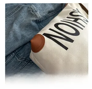 Detail of canvas tote bag with fashion print, reinforced leather corners and precise stitching