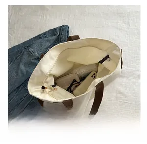 Spacious interior of white canvas tote bag showing storage for phone, wallet and umbrella