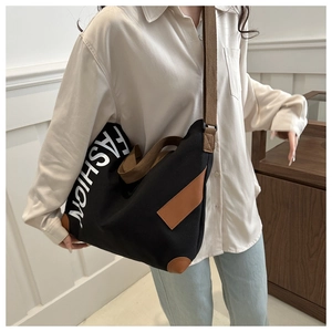 Detail of black canvas tote bag showing fashion print and brown leather patch accents