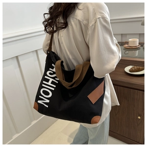 Detail of fashion canvas tote bag with leather corners and white text print on back