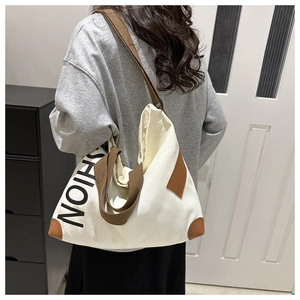 Detail of canvas tote bag showing brown leather reinforced corners and shoulder strap texture