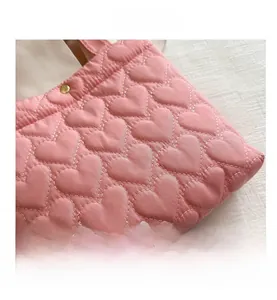 Macro detail of pink quilted tote bag showing heart pattern stitching and metal snap button