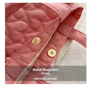 Detail of pink quilted tote bag showing the golden magnetic snap button and heart pattern
