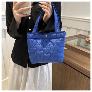 Detail of royal blue tote bag featuring 3D heart quilting and gold snap fastener