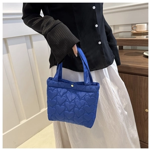 Detail of royal blue tote bag with heart-shaped quilted texture and gold snap button