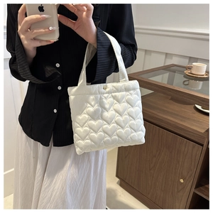 Close-up of white heart-shaped quilted pattern and metallic snap button on tote bag