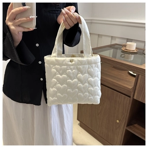 Close-up of white heart-quilted tote bag with premium textured fabric and soft handles
