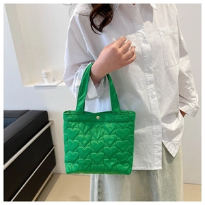 Detail of bright green tote bag featuring heart quilted texture and gold metal clasp