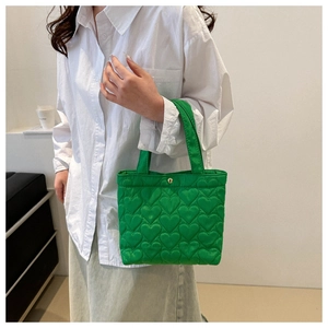 Detailed view of heart-quilted green tote bag with premium gold snap button closure