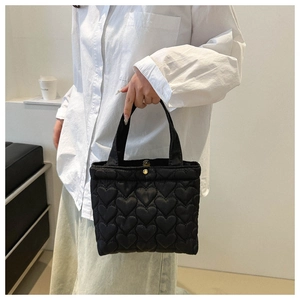 Detail of black heart-quilted tote bag fabric with elegant gold snap button closure