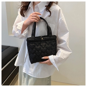 Close-up of black tote bag featuring heart-shaped quilting and a gold magnetic closure