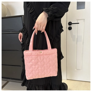 Detailed view of pink heart-quilted tote bag featuring golden snap button and soft fabric