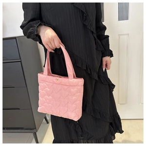 Detailed shot of pink heart-quilted tote bag with gold button and dual handles